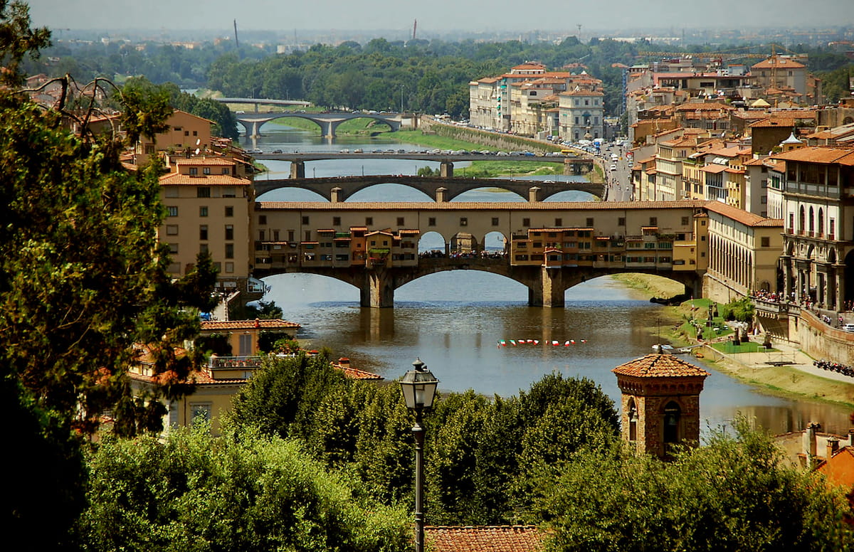 The Ponte Vecchio bridge reflected in the golden waters of the Arno River at sunset in Florence