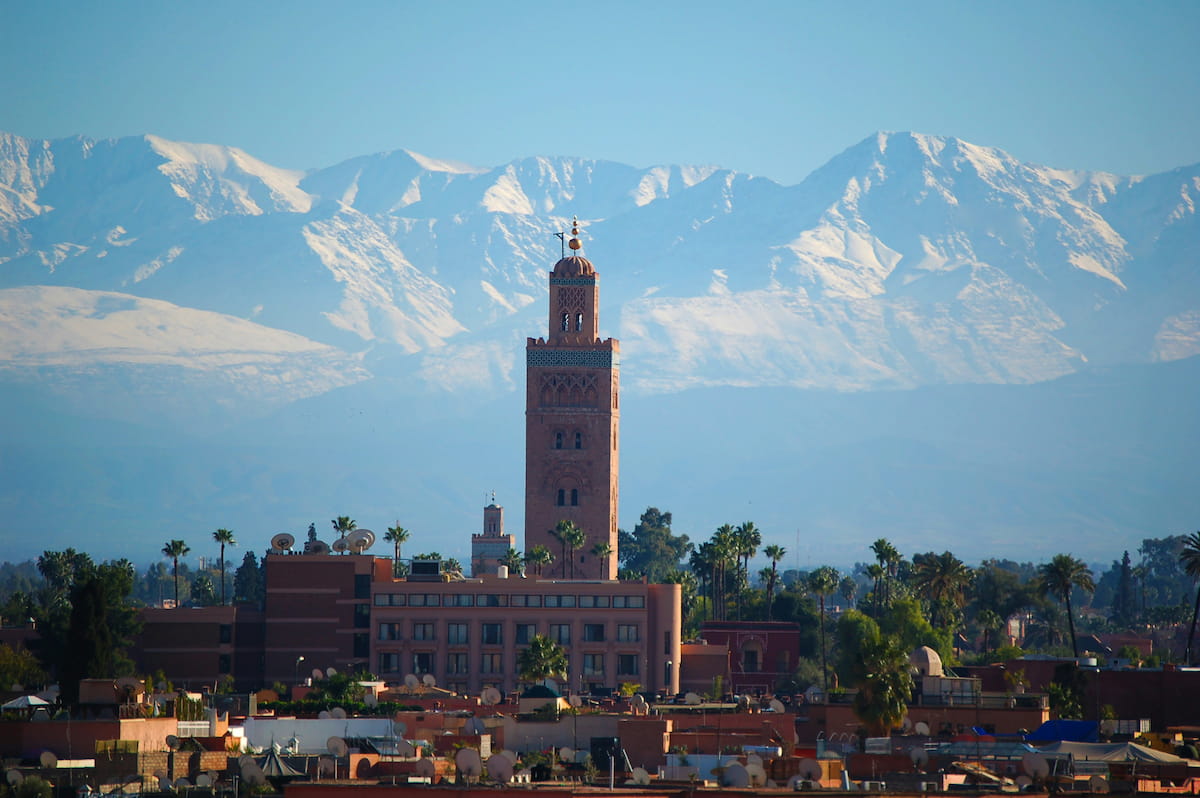 Marrakech medina rooftop view with Koutoubia Mosque and Atlas Mountains at golden hour