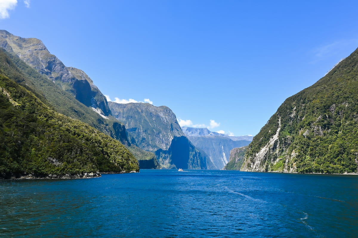 Kayakers on Milford Sound, New Zealand, with towering granite cliffs and waterfalls