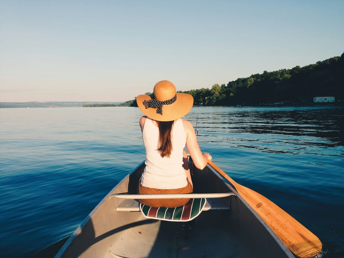 Solo kayaker on calm Finger Lakes water at golden morning light
