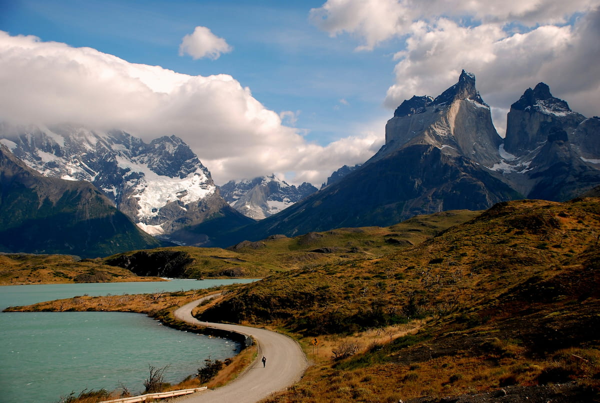 Hiker on a trail in Torres del Paine with the dramatic Cuernos del Paine peaks in the background
