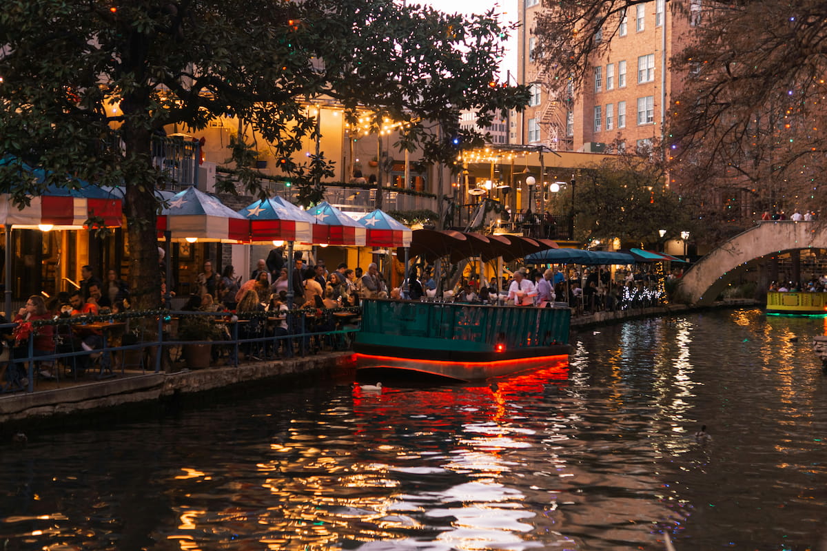San Antonio River Walk with lush cypress trees lining the water and stone bridges